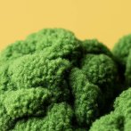 Jellycat Brokkoli Amuseables Broccoli, Nahaufnahme Brokkoliröschen vor einem gelben Hintergrund