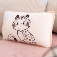 rechteckiges NICI Wild Winter Kissen Schneeleopard Eleni Snowbell auf einem hellen Sofa